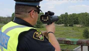 An Ontario Provincial Police officer with a radar speed gun. (Photo by OPP)