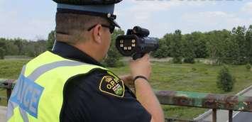 An Ontario Provincial Police officer with a radar speed gun. (Photo by OPP)